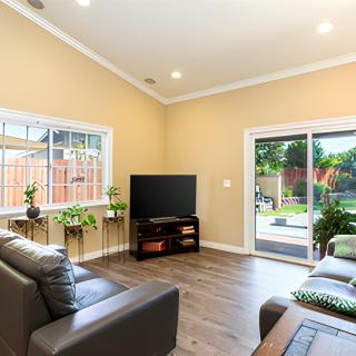 A modern living room with comfortable sofas, a television, and natural lighting from large windows and a sliding door.