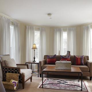 A cozy living room with a sofa, armchair, coffee table, and soft lighting.