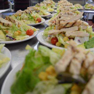 Plates of chicken salad arranged in a line, featuring lettuce, tomatoes, and vegetables.