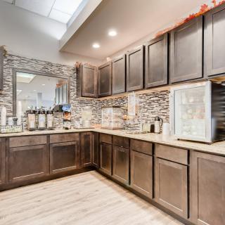 A modern kitchen interior featuring dark wooden cabinets, a well-equipped coffee station, and sleek countertops.