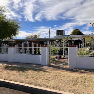 A charming suburban home with a white picket fence and a well-maintained garden under a cloudy sky.