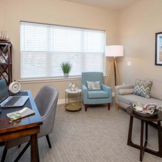 A cozy home office with a desk, chairs, and a sofa.