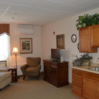 A cozy living area with an armchair, sofa, television, and kitchenette.