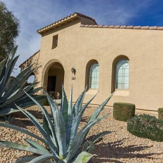 A house with a desert landscape featuring succulents under a clear blue sky.