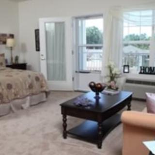 A cozy bedroom with elegant decor, featuring a bed, coffee table, and large windows letting in natural light.