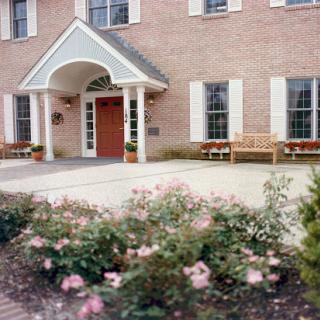 A welcoming entrance to a brick building, adorned with blooming flowers and benches.
