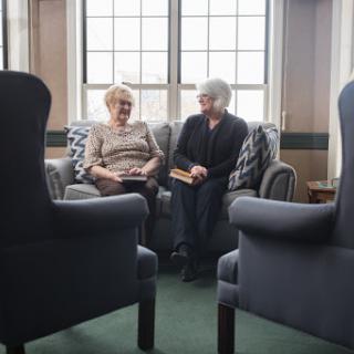 Two seniors engaged in a heartfelt conversation on a cozy couch.