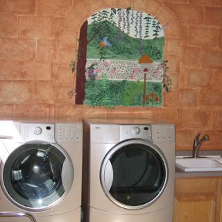 A stylish laundry area featuring modern washing machines and a decorative piece above.