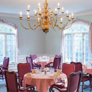 An elegant dining room with a large chandelier and tables set for a formal meal.
