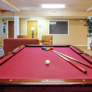 A cozy recreation room featuring a red pool table with cue sticks and billiard balls set for a game.