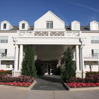 A grand entrance with white columns and landscaped flower beds.