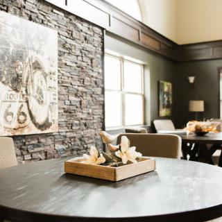 A modern lounge area featuring a round table, stone accent wall, and stylish decor.