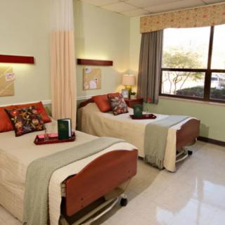 A well-decorated hospital room with two patient beds and a large window.