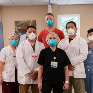 A dedicated healthcare team posing together in a medical facility, showcasing their commitment and protective measures during the pandemic.
