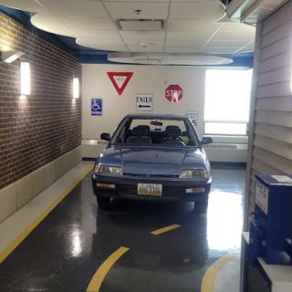 A blue car parked indoors near traffic signs.