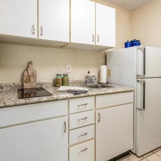 A compact kitchen with white cabinets and a refrigerator.