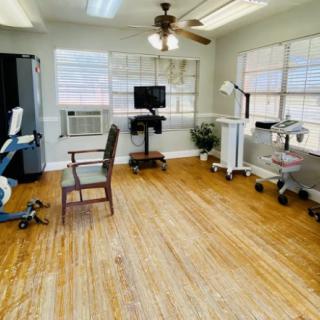 A clean and organized medical office with various equipment and wooden flooring.