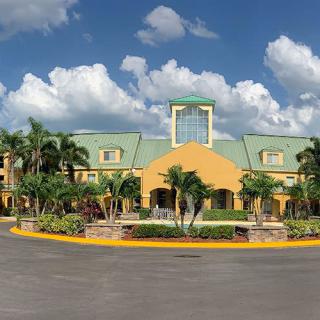 A tropical resort building with palm trees under a blue sky with clouds.