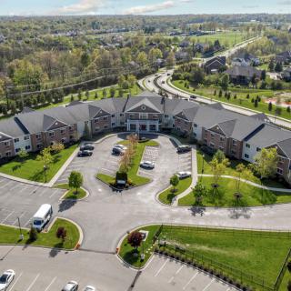 Aerial view of a large residential building with a surrounding parking lot and extensive greenery.
