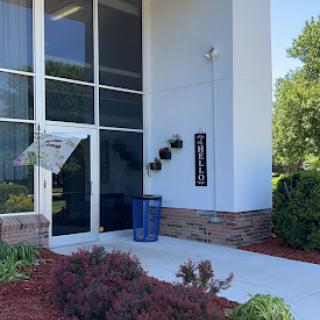 A modern building entrance featuring large windows and decorative planters.