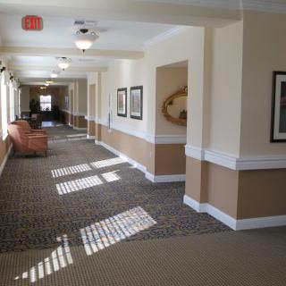 A well-lit hallway with carpeted floors and wall decorations.