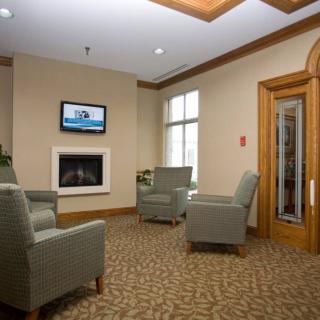 A comfortable lobby with armchairs, a fireplace, and a TV.