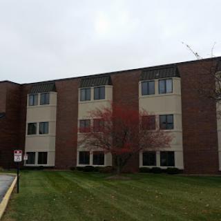 A residential apartment building showcasing a brick facade and well-maintained lawn.