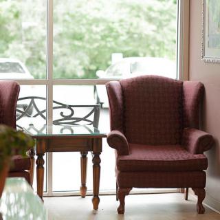 Cozy chairs and a small table by a large window in a sunlit living room.
