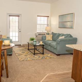 A cozy living room featuring a blue sofa, coffee table, and warm decor.