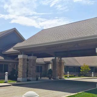A spacious building with a covered entrance and driveway under a clear sky.