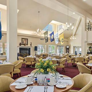 A well-decorated dining room with elegant tables, chairs, and chandeliers.
