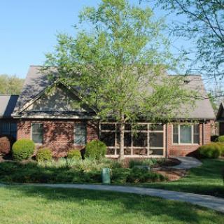 A charming residential house surrounded by a well-maintained garden and a large tree.