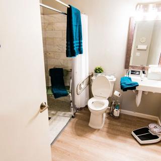 A clean and modern bathroom with a shower, toilet, vanity mirror, and towels.