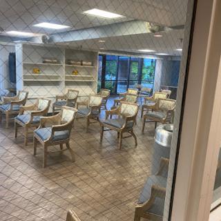 A spacious and empty dining area featuring several tables and chairs, with natural light coming through the windows.