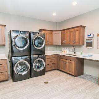 A modern laundry room featuring stacked washer and dryer units along with wooden cabinetry.