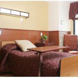 A well-arranged hospital room with a single bed, chair, and side table.