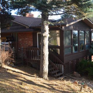 A cozy cabin-like house surrounded by trees with sunlight filtering through.