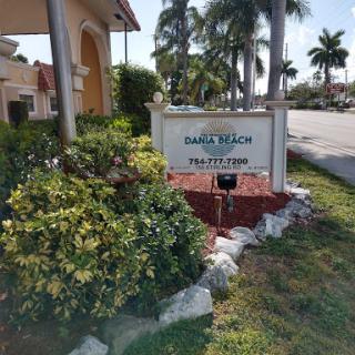 A welcoming sign for a residential community, surrounded by lush greenery and palm trees.