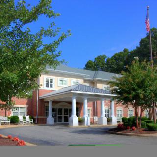 A large building with a prominent entrance, surrounded by trees and displaying a flag.