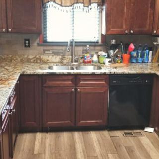A cozy kitchen with wooden cabinets and a granite countertop.