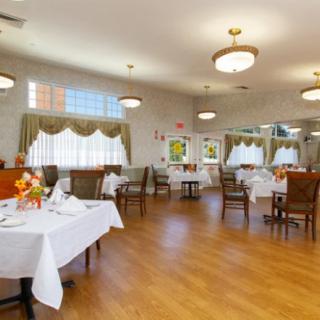 A well-lit dining room with neatly arranged tables and chairs, featuring elegant decor and wooden floors.