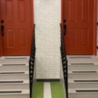A symmetrical indoor staircase leading to two red doors.