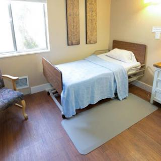 A cozy hospital room featuring a single bed, a chair, and natural light coming through the window.