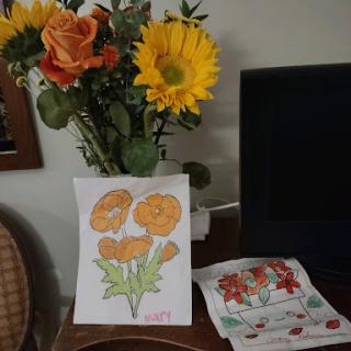 A vibrant display of fresh flowers alongside a colorful artwork of orange flowers and decorative napkins.
