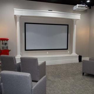 A cozy home theater setup with a projector screen and comfortable seating.