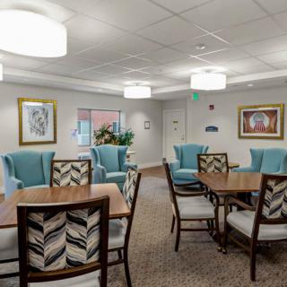 A modern lounge area with comfortable seating and tables, adorned with artwork and bright lighting.