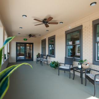 A cozy outdoor porch with seating, ceiling fans, and plants.