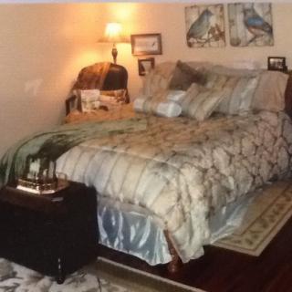 A cozy bedroom featuring a neatly made bed with multiple pillows, a bedside lamp, and decorative artwork on the walls.