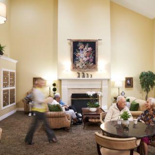 A comfortable common area in a senior living facility where elderly residents engage in conversation and relaxation.