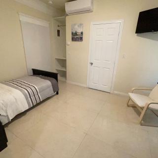 A minimalist bedroom with a single bed, chair, and wall-mounted TV.